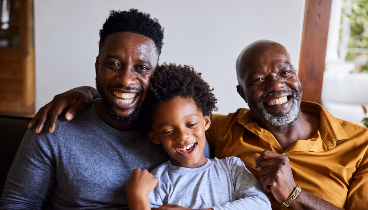 A family of three sitting on a couch and laughing.